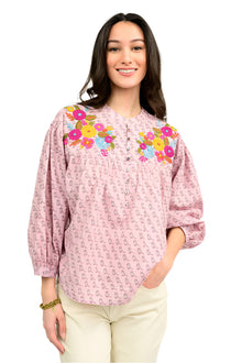  Woman wearing a pink blouse with floral embroidery on a white background