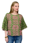 Woman wearing a green and pink patterned blouse against a plain background
