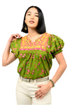 Woman wearing a green floral blouse with pink accents on a white background