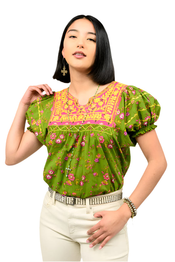 Woman wearing a green floral blouse with pink accents on a white background
