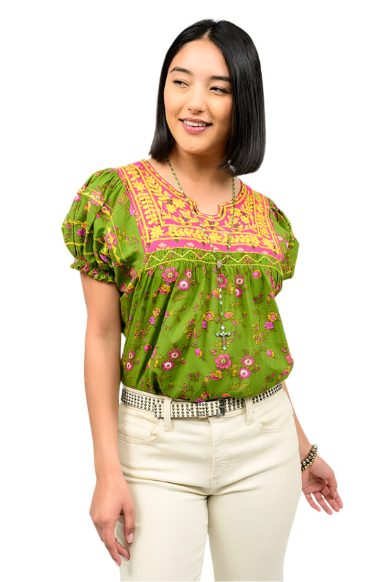 Woman wearing a green floral blouse with pink accents on a white background