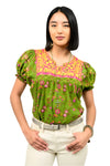 Woman wearing a green floral blouse with pink accents on a white background
