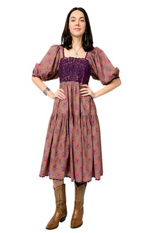  Woman wearing a floral dress with a purple top and brown boots on a white background