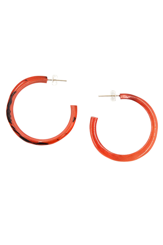 Pair of orange hoop earrings on a white background