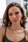 Woman wearing colorful earrings with a blurred outdoor background