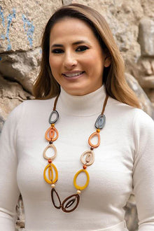  Woman wearing a long, colorful necklace against a stone wall background