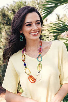  Woman wearing a colorful necklace outdoors with greenery in the background
