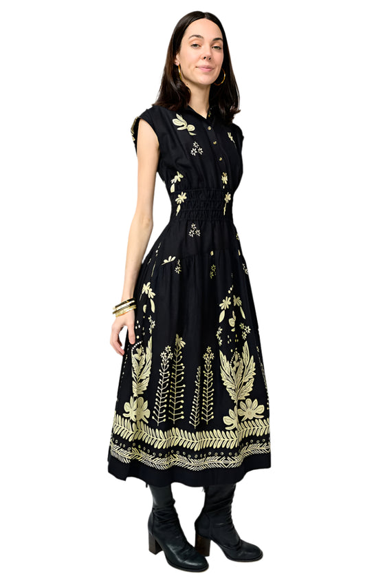 Woman wearing a black dress with gold embroidery on a white background