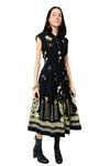 Woman wearing a black dress with gold floral patterns on a white background