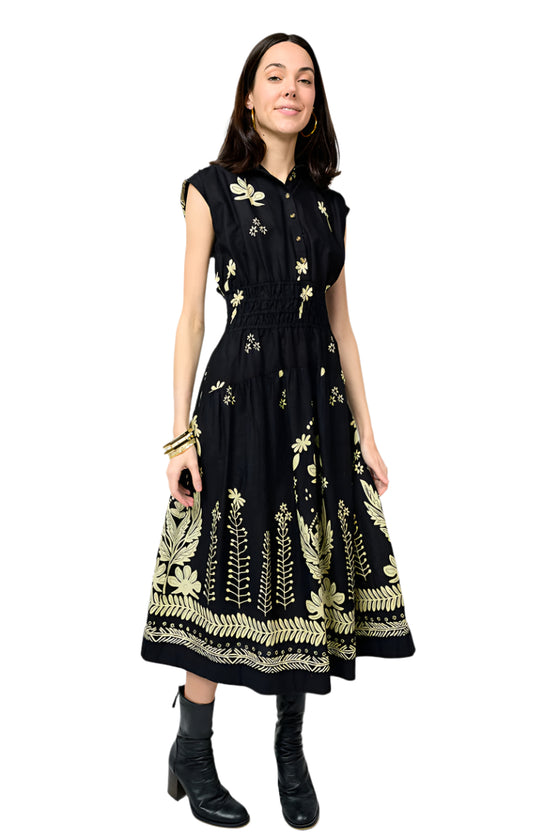 Woman wearing a black dress with gold floral patterns on a white background
