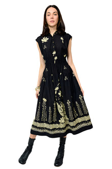  Woman wearing a black dress with gold floral embroidery on a white background