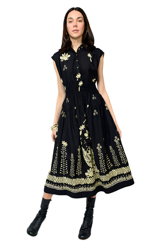 Woman wearing a black dress with gold floral embroidery on a white background